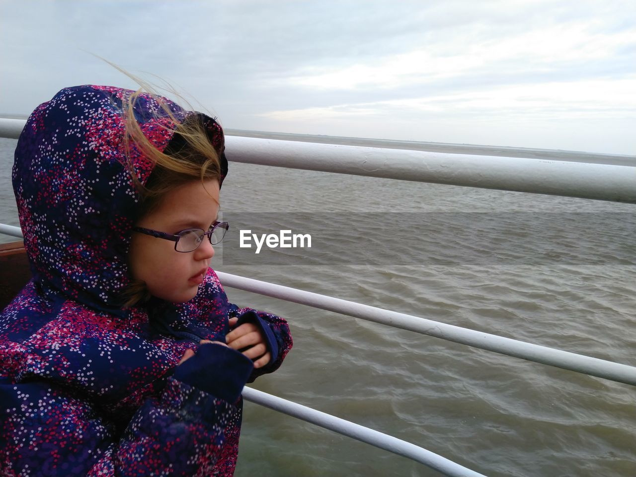 Side view of young girl with glasses on railing