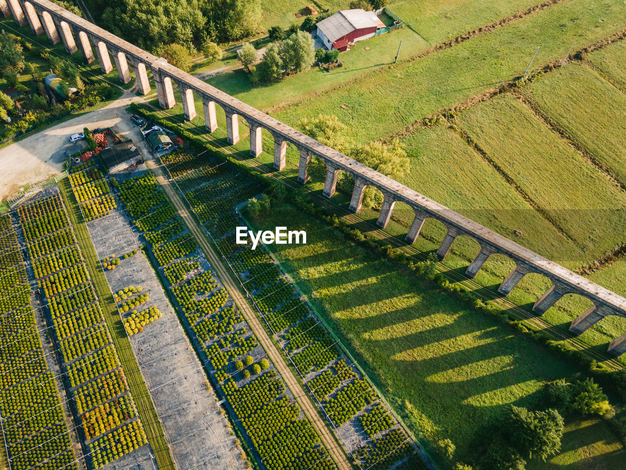 Aerial shot of old aqueduct and vegetables, plants farmland in italy