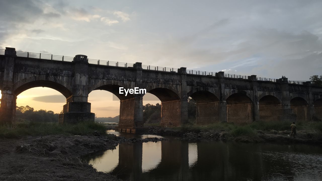 Arch bridge over river against sky