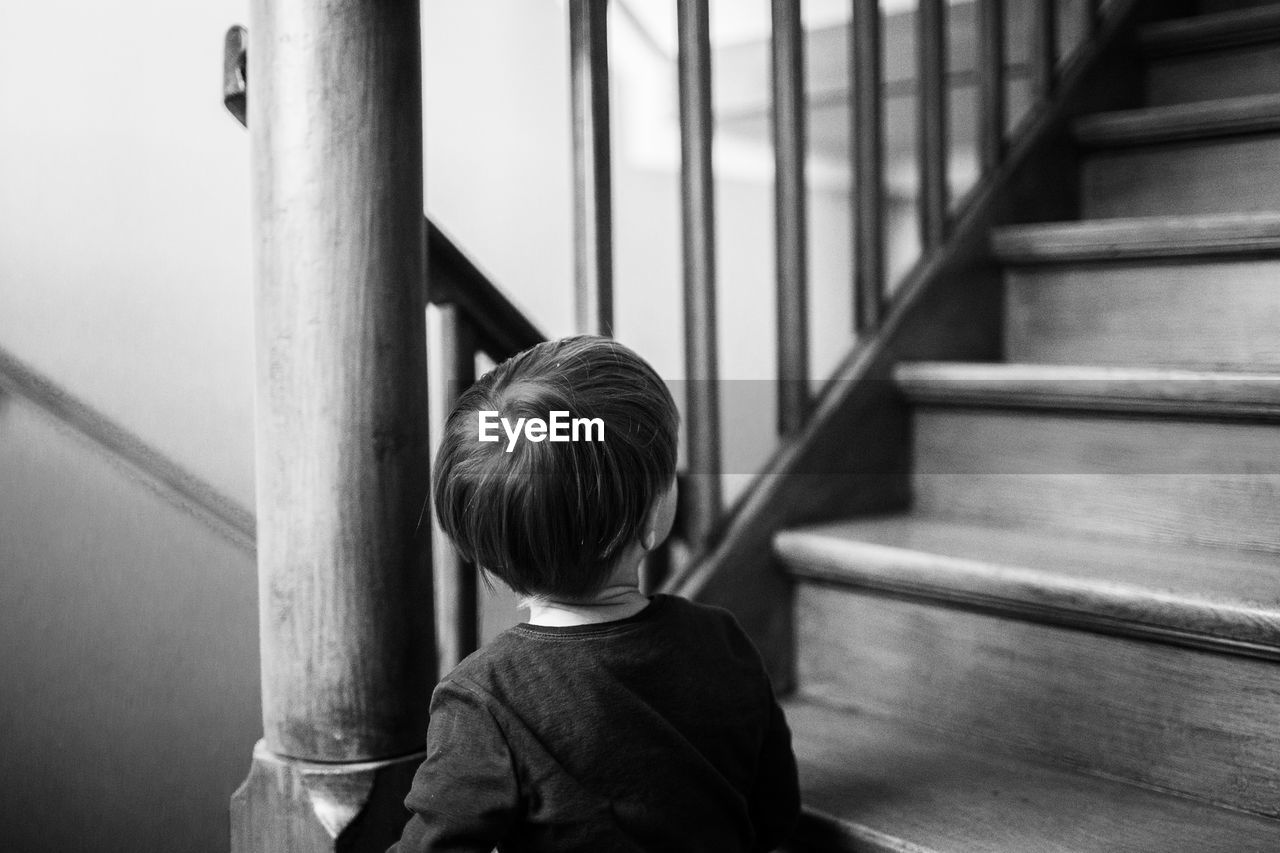 Rear view of boy by standing by staircase at home