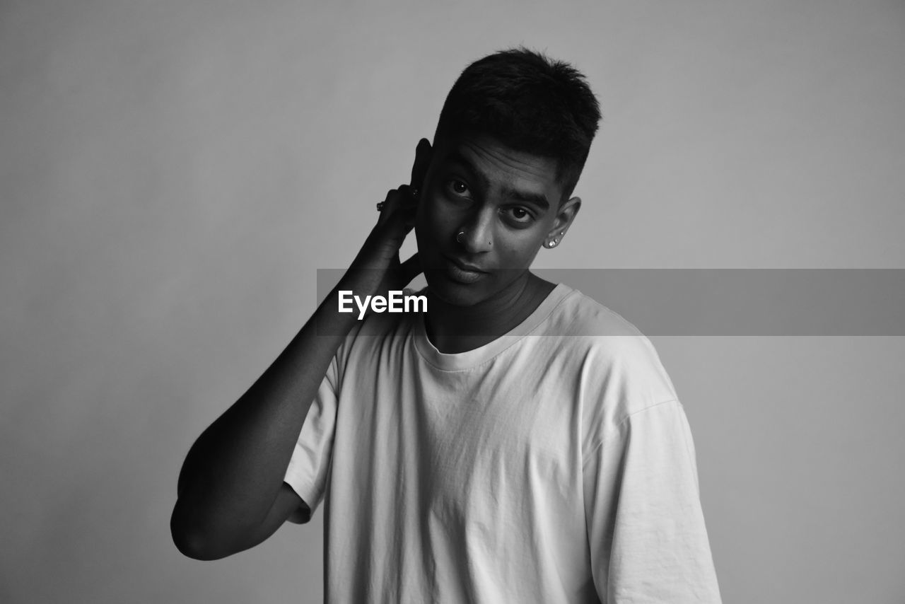 Portrait of young man standing against backdrop