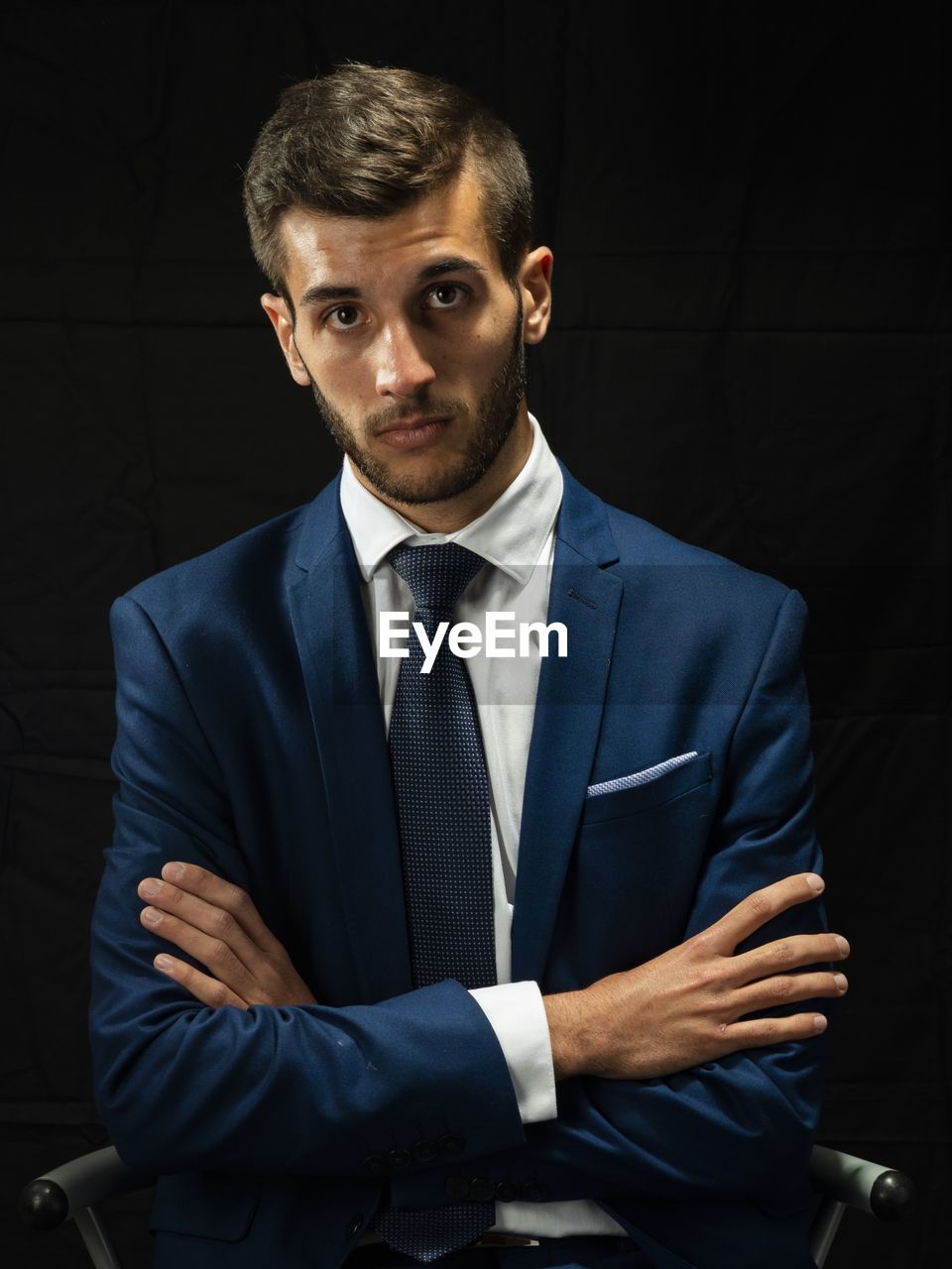 Portrait of young man in suit sitting against black background