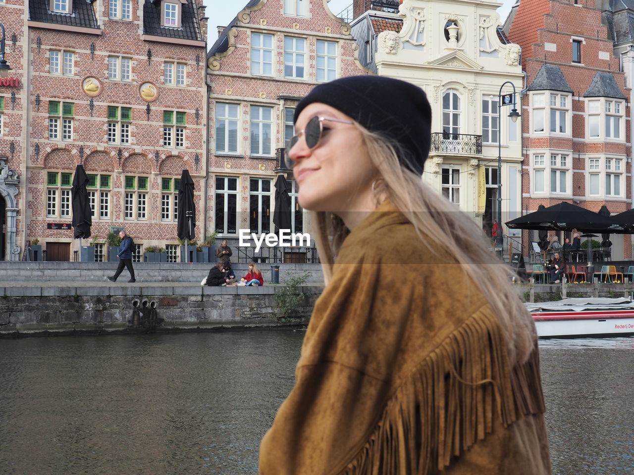 BEAUTIFUL YOUNG WOMAN IN CITY AGAINST CANAL