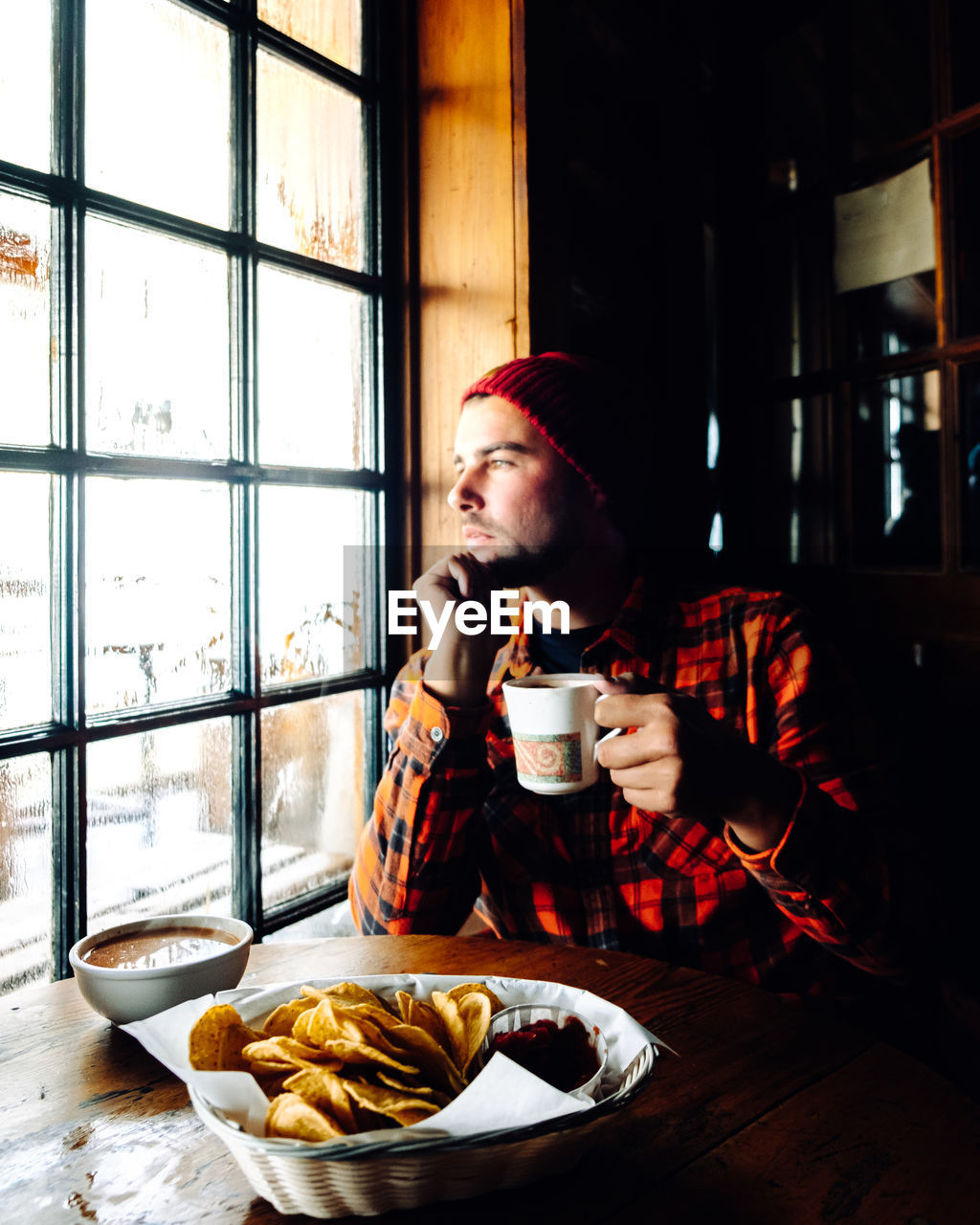 Young man drinking coffee while sitting on table at home