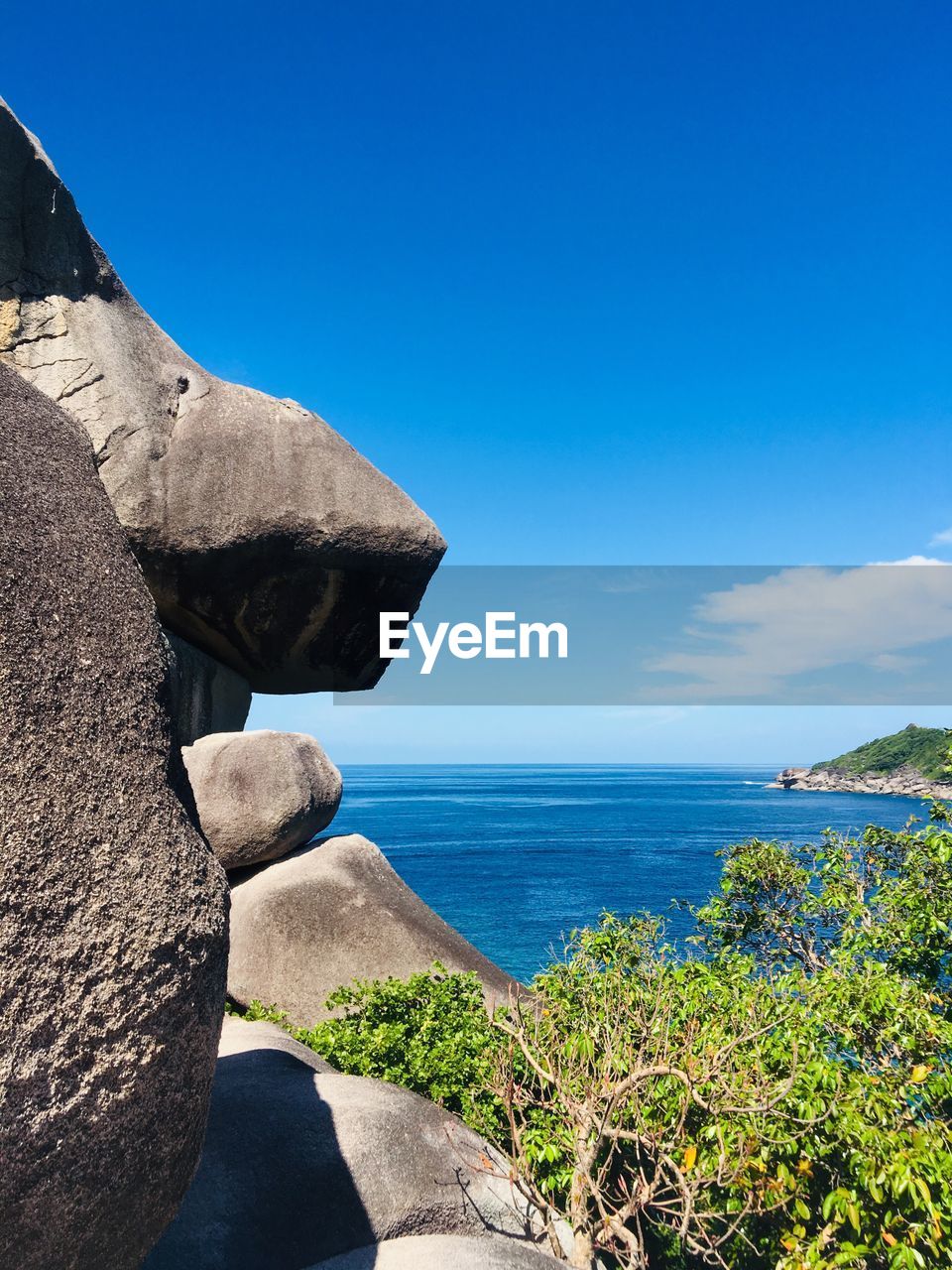 Scenic view of rocks by sea against blue sky