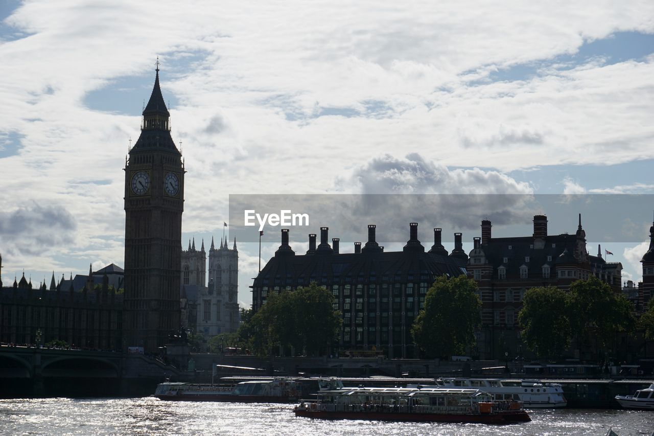 Thames river and big ben against cloudy sky