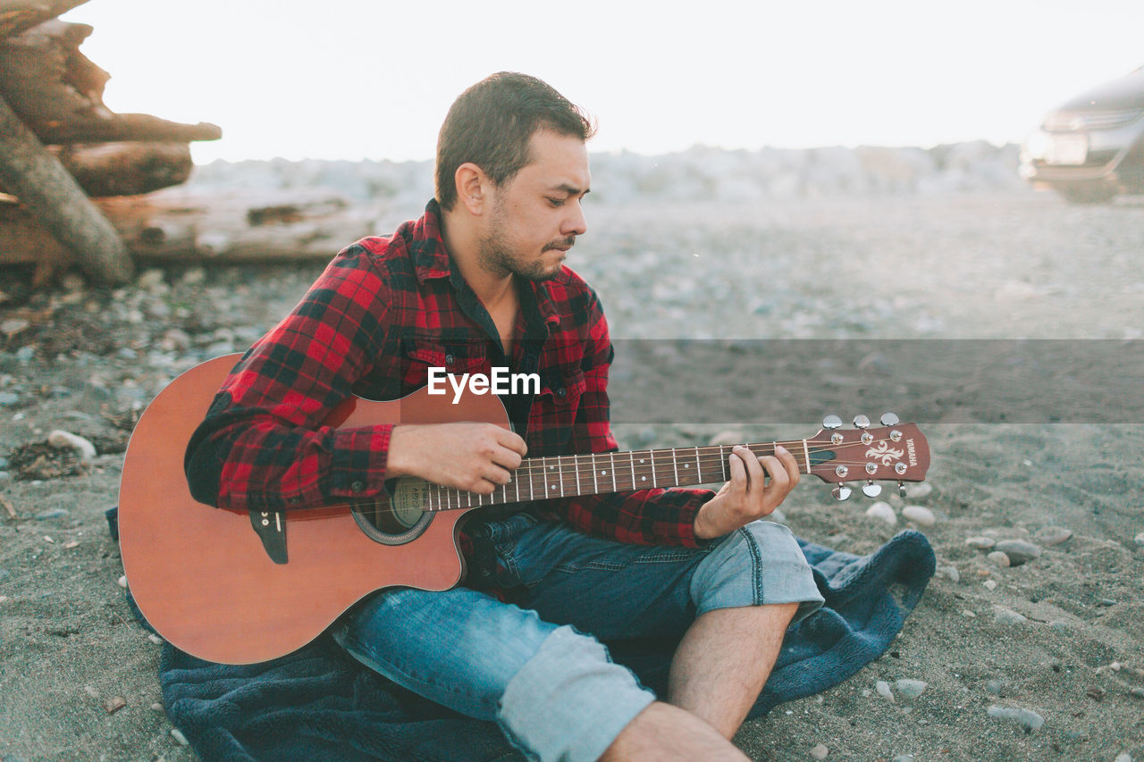 Man playing guitar while sitting outdoors