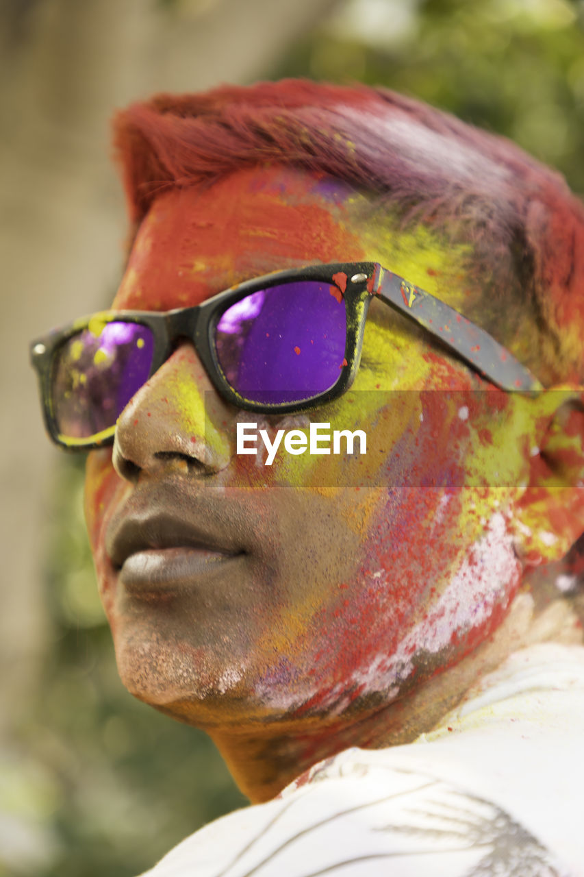 Close-up of man with powdered paint on face wearing sunglasses during holi