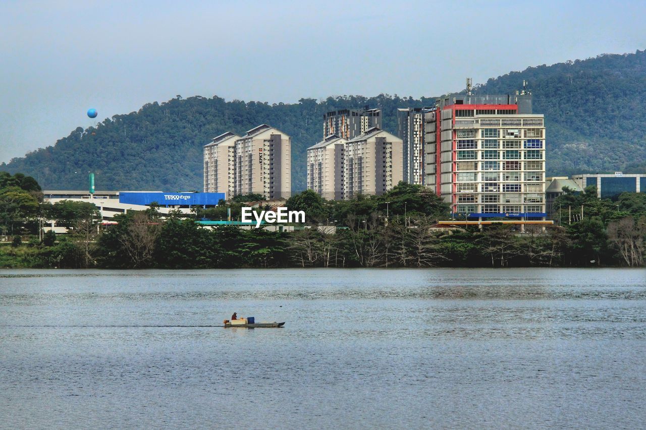 Scenic view of lake by buildings against sky