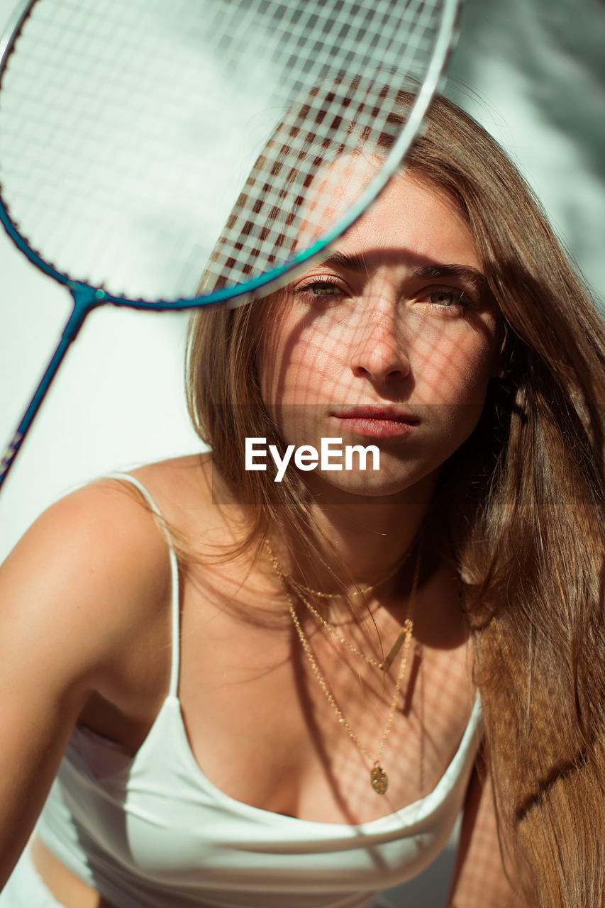 Close-up portrait of beautiful young woman holding racket