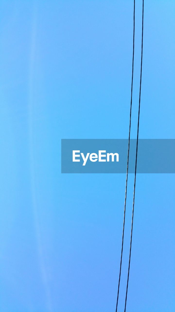 LOW ANGLE VIEW OF POWER LINES AGAINST CLEAR BLUE SKY