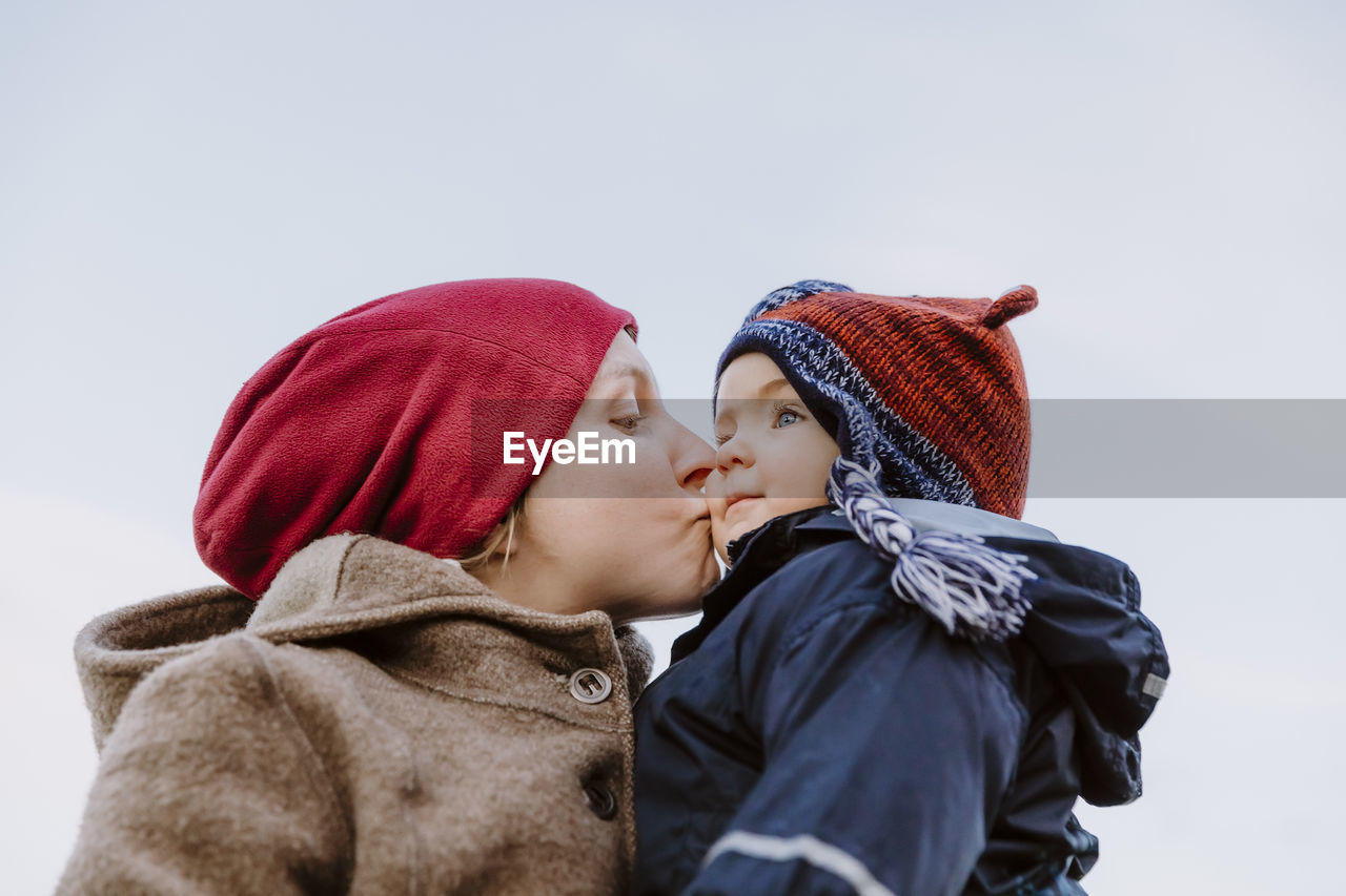 Low angle view of mother with son against clear sky