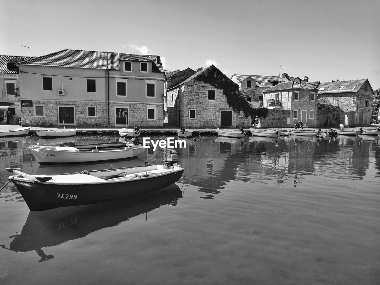 BOATS MOORED ON CANAL BY BUILDINGS AGAINST SKY