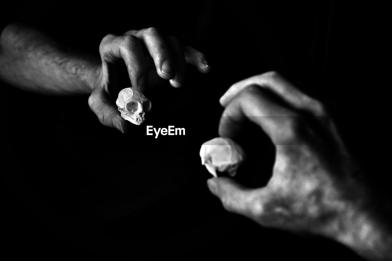 Cropped hand holding human skill reflecting on mirror in darkroom