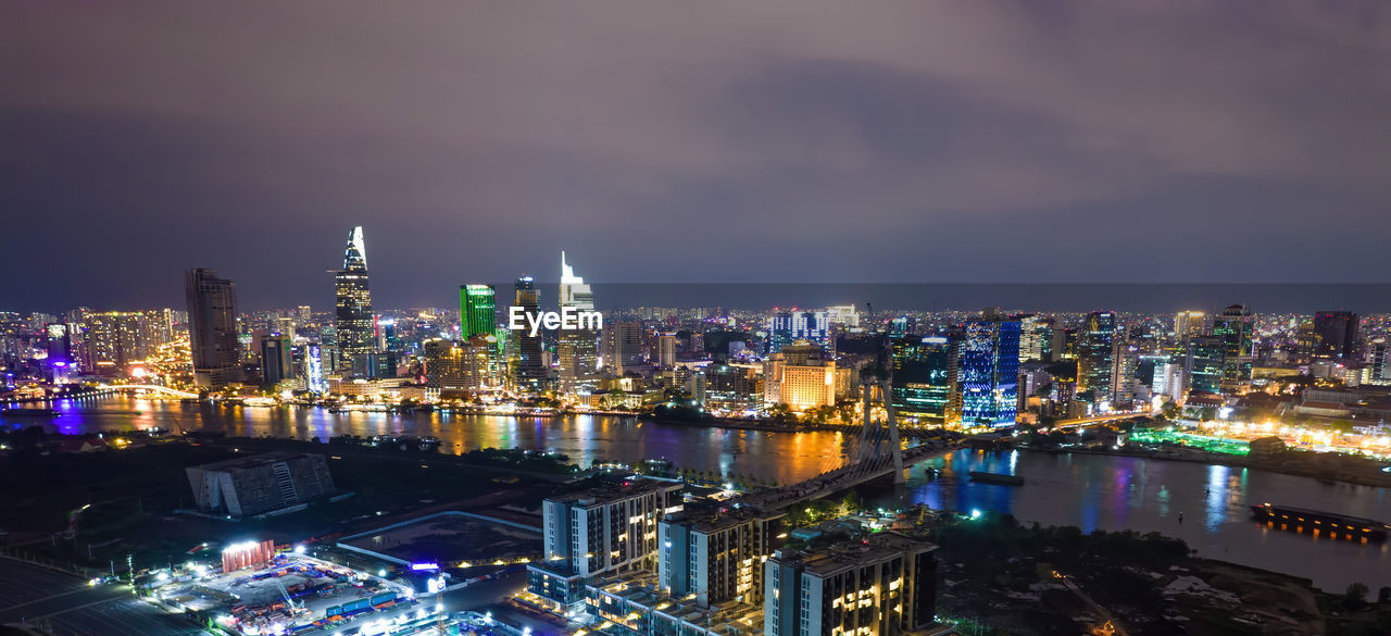 HIGH ANGLE VIEW OF ILLUMINATED MODERN BUILDINGS AGAINST SKY