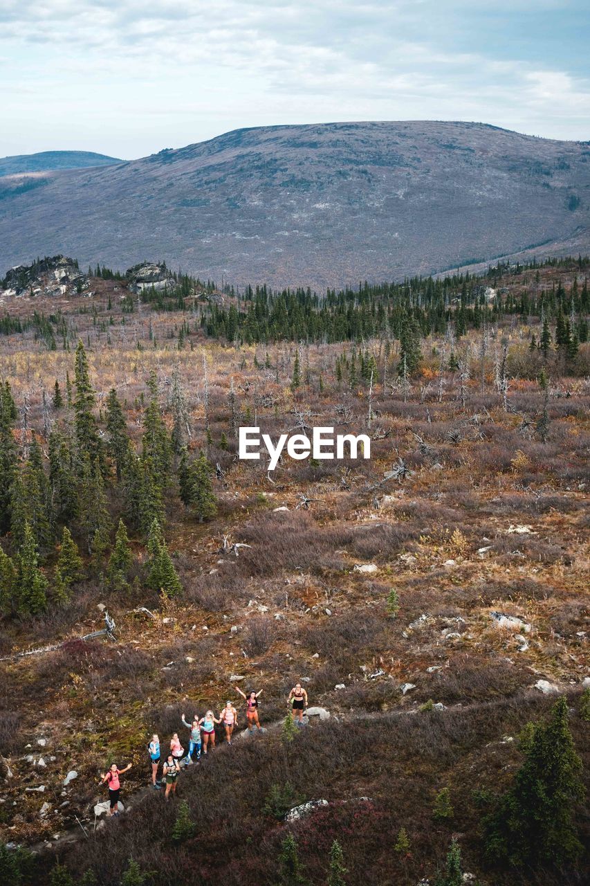 GROUP OF PEOPLE ON LANDSCAPE AGAINST MOUNTAINS