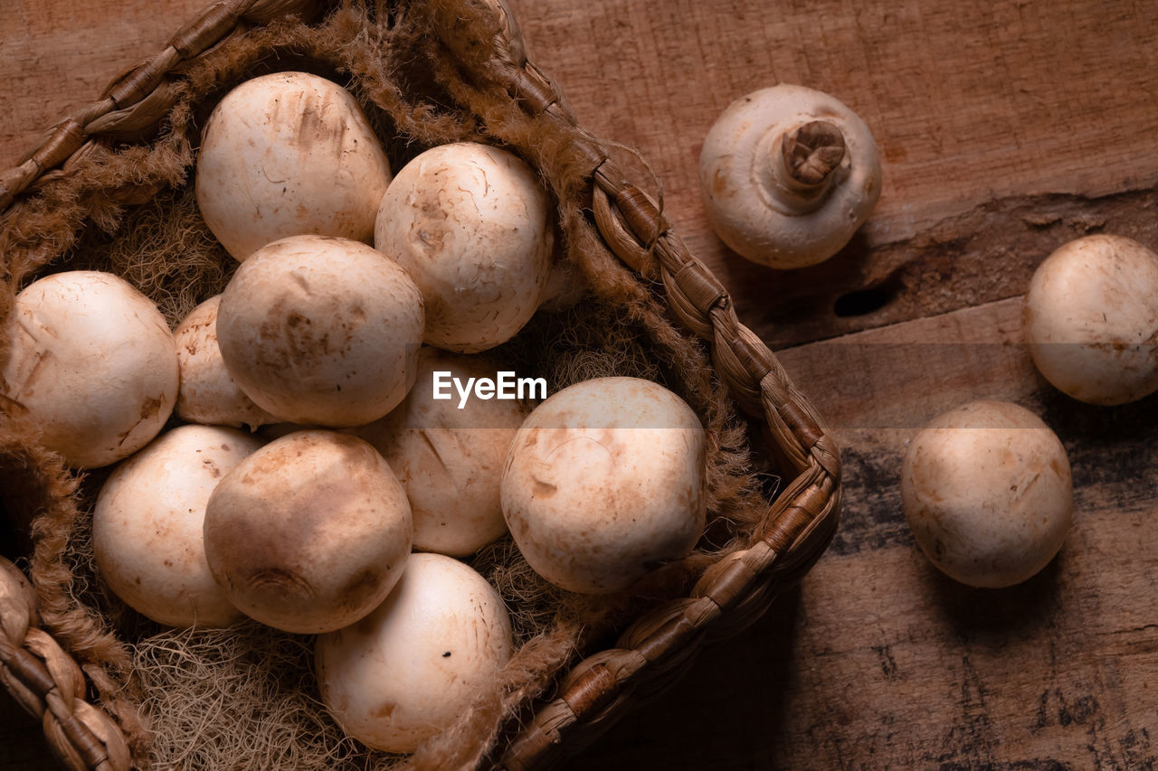 High angle view of button mushroom in basket on wooden table