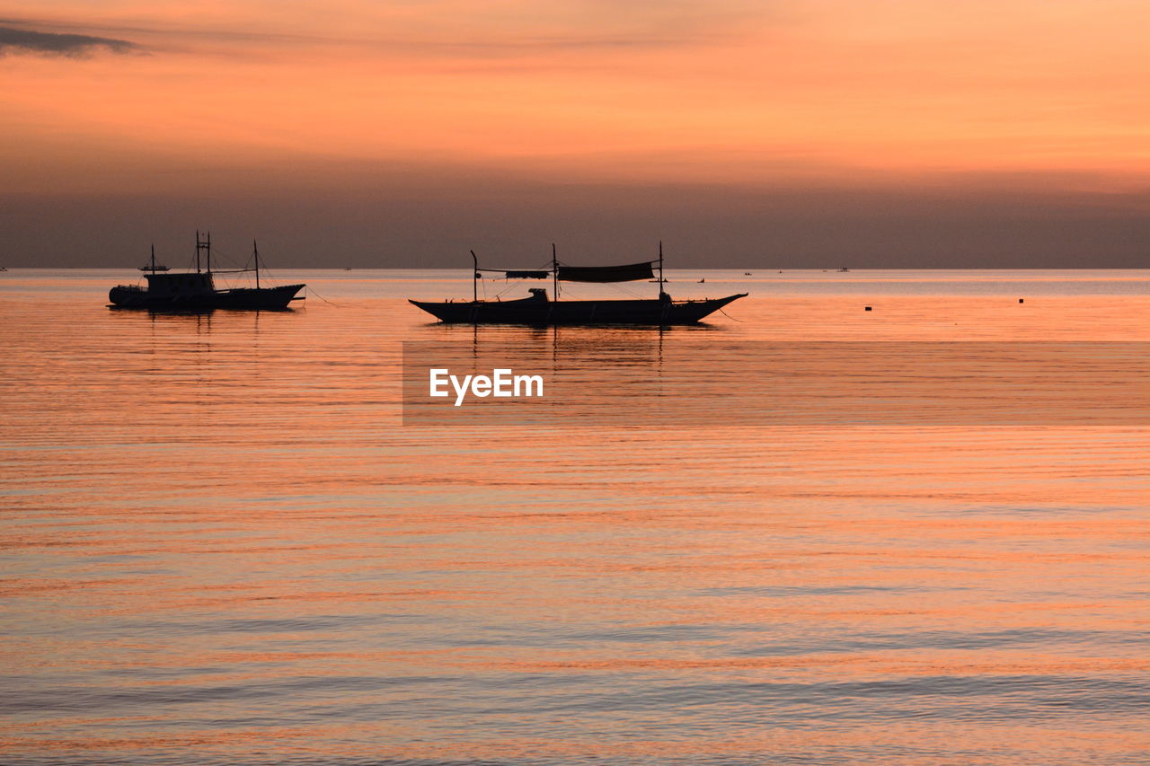 SILHOUETTE SAILBOAT IN SEA AGAINST ORANGE SKY