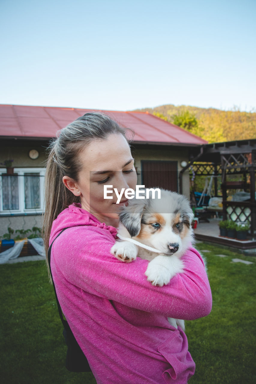 Girl holds smiling australian shepherd puppy. love and relationship between female dog and female