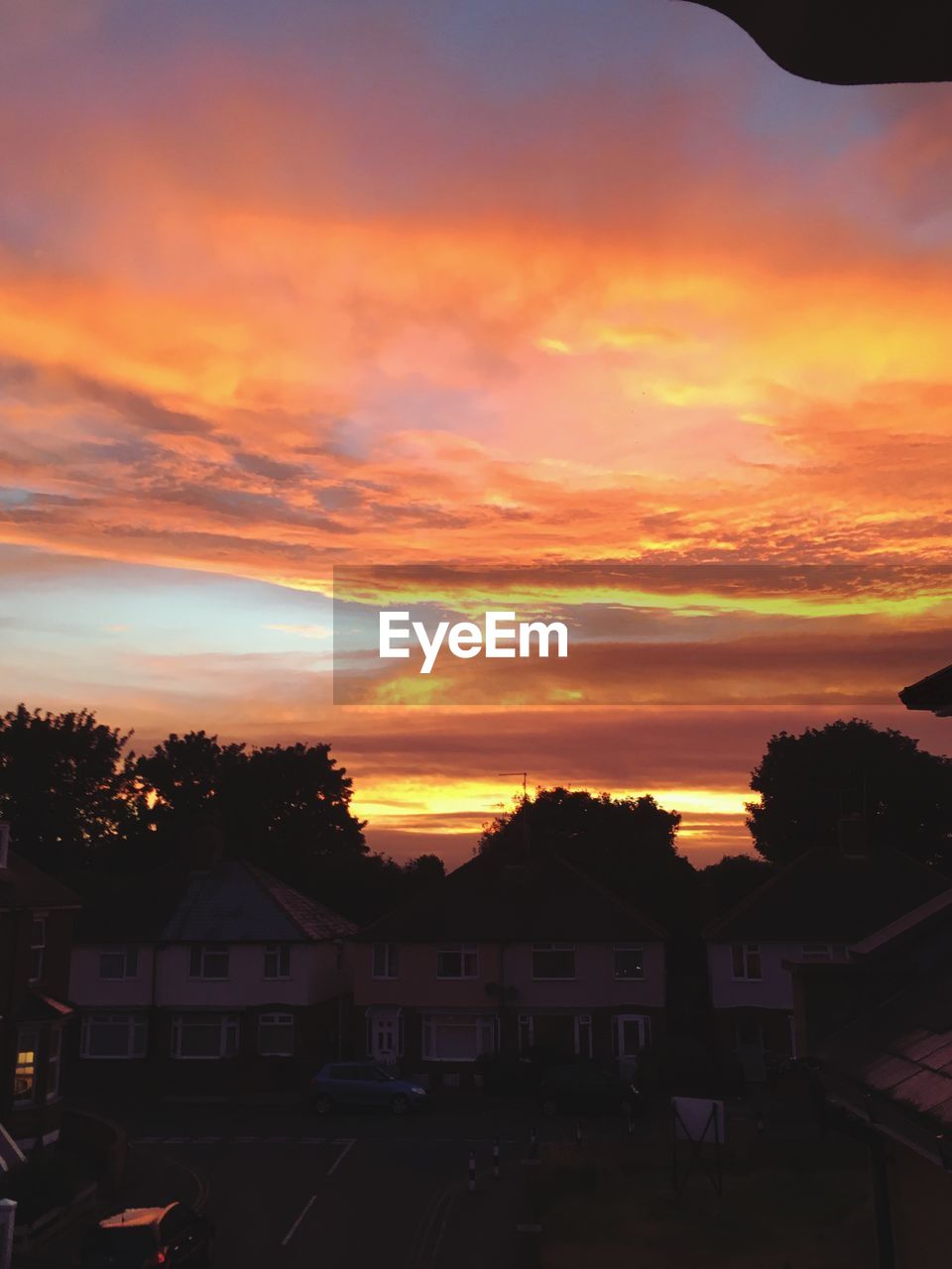 SILHOUETTE OF HOUSES AGAINST DRAMATIC SKY