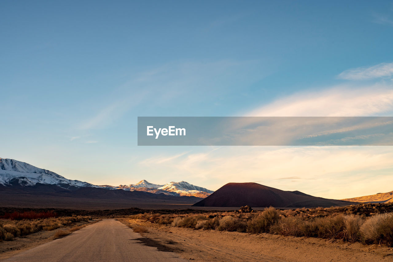 Dirt road in desert against sky