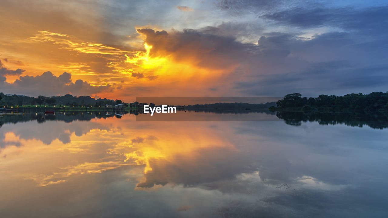 Scenic view of lake against dramatic sky during sunset
