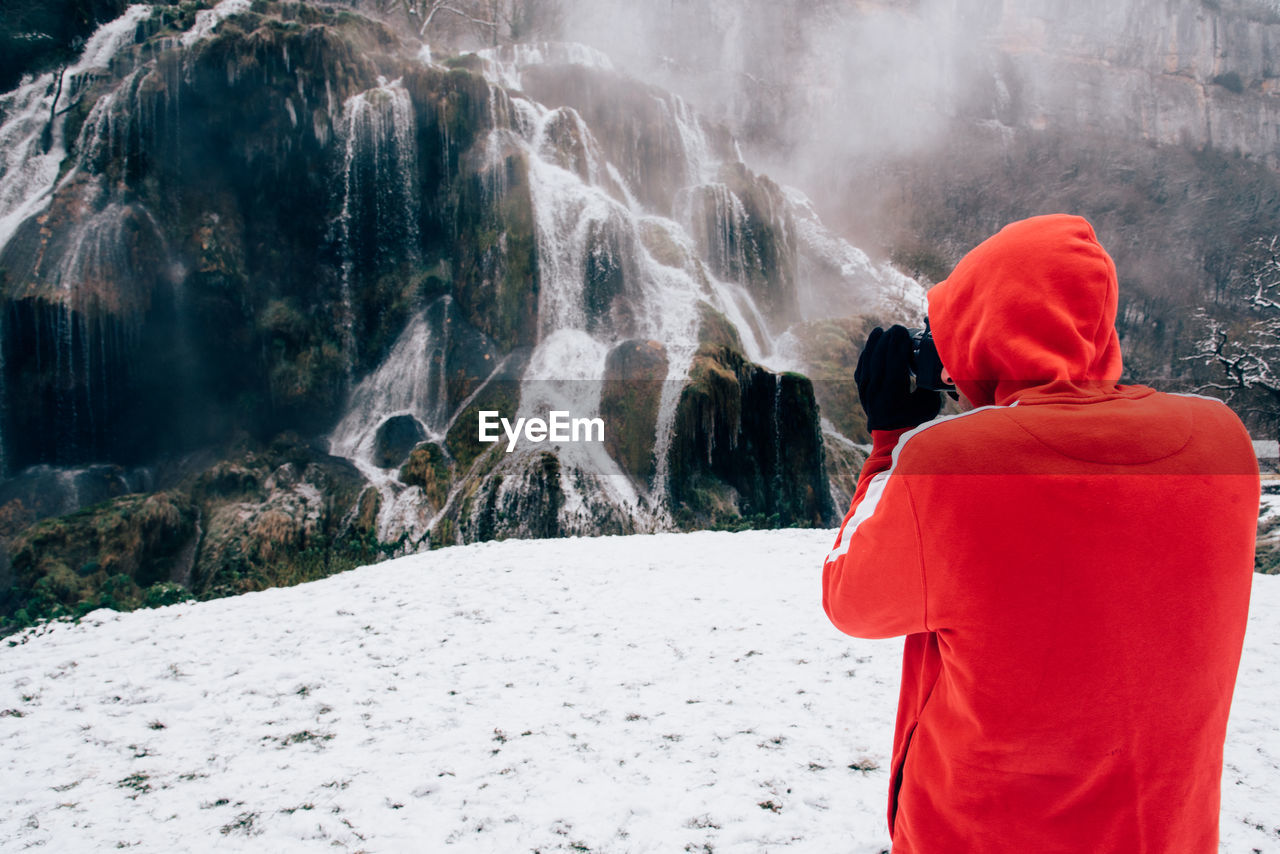 Man photographing waterfall during winter