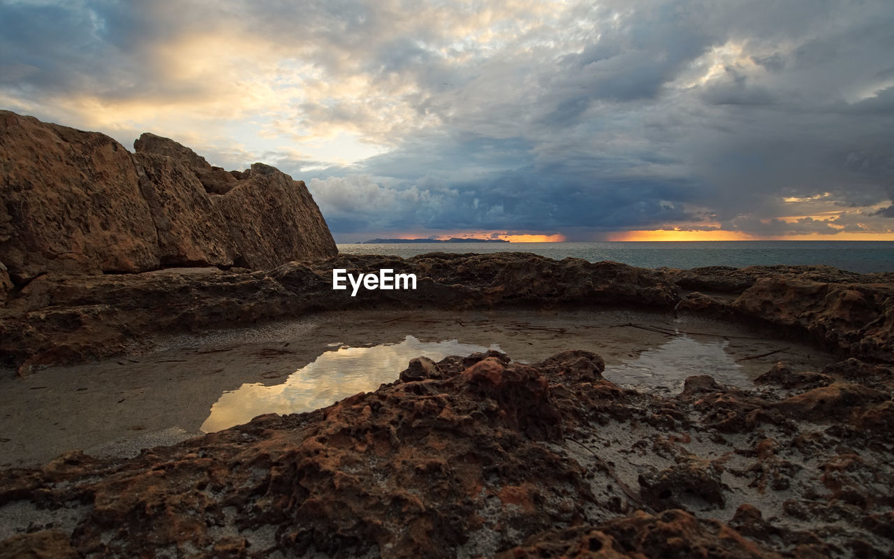 Rock formations in sea against sky during sunset