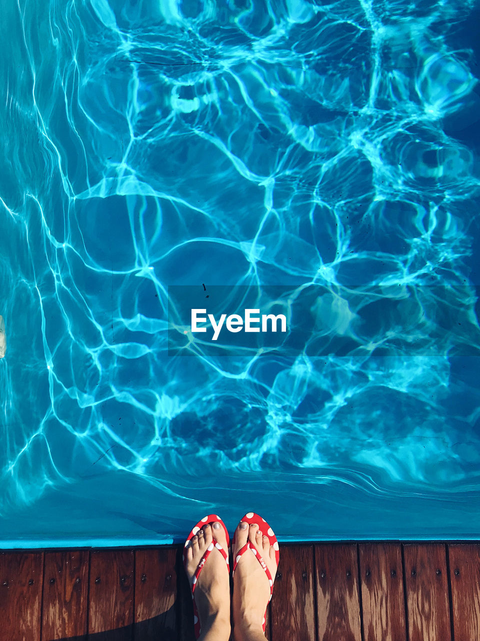 Low section of woman standing at poolside