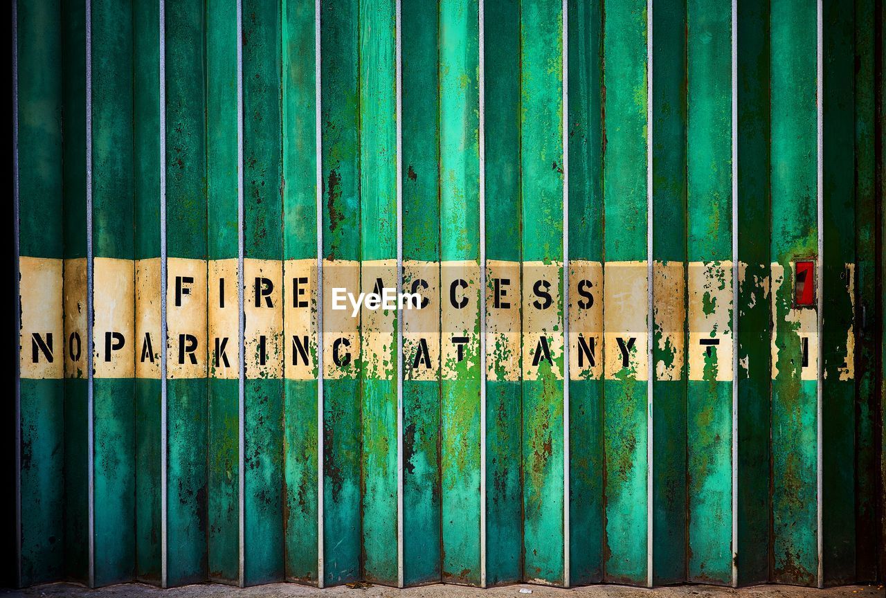 Close-up of text on old metal fence