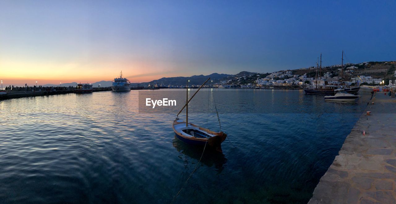 Sailboats moored in river against sky during sunset