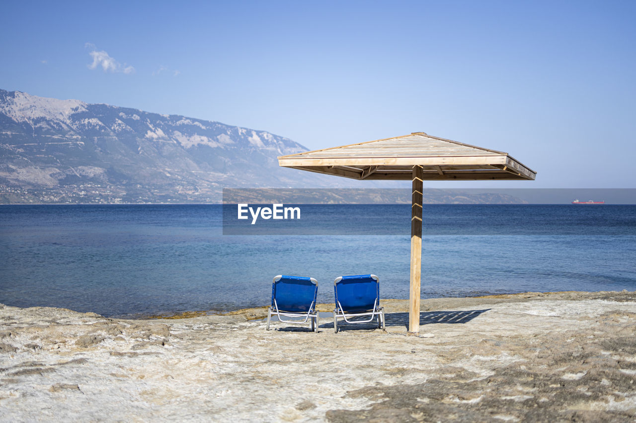 Chair on beach against blue sky