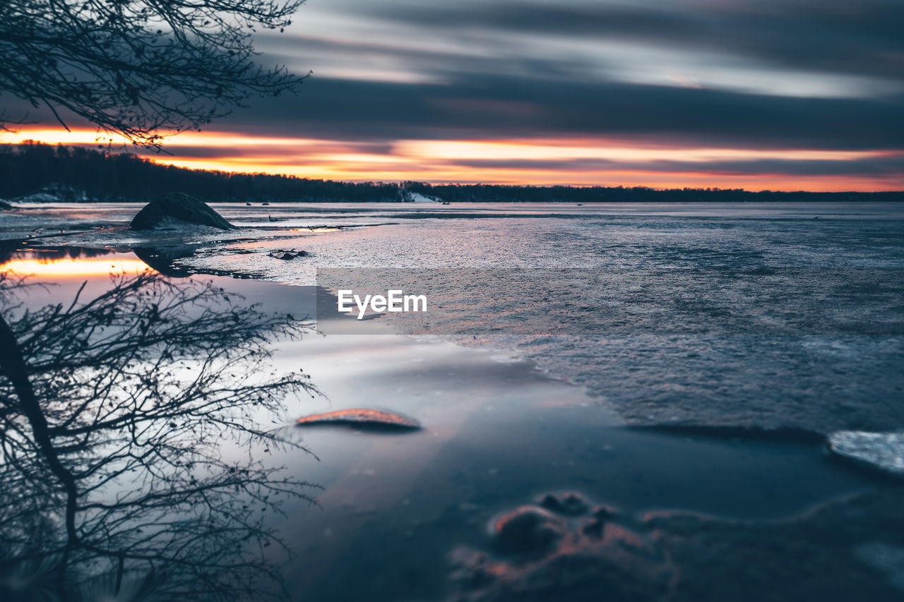 Scenic view of lake against sky during sunset during winter