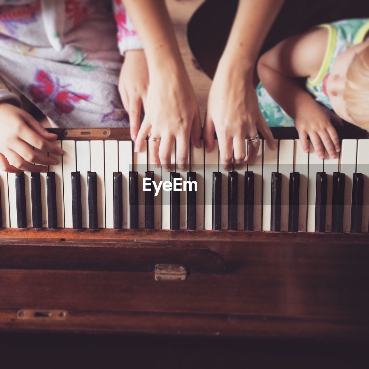 Cropped image of mother teaching daughters to play piano