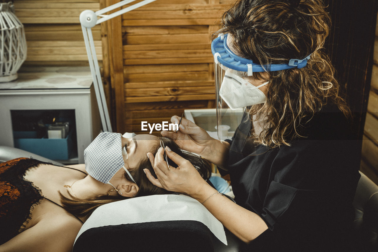 Beautician working with mask and protective screen for the virus covid