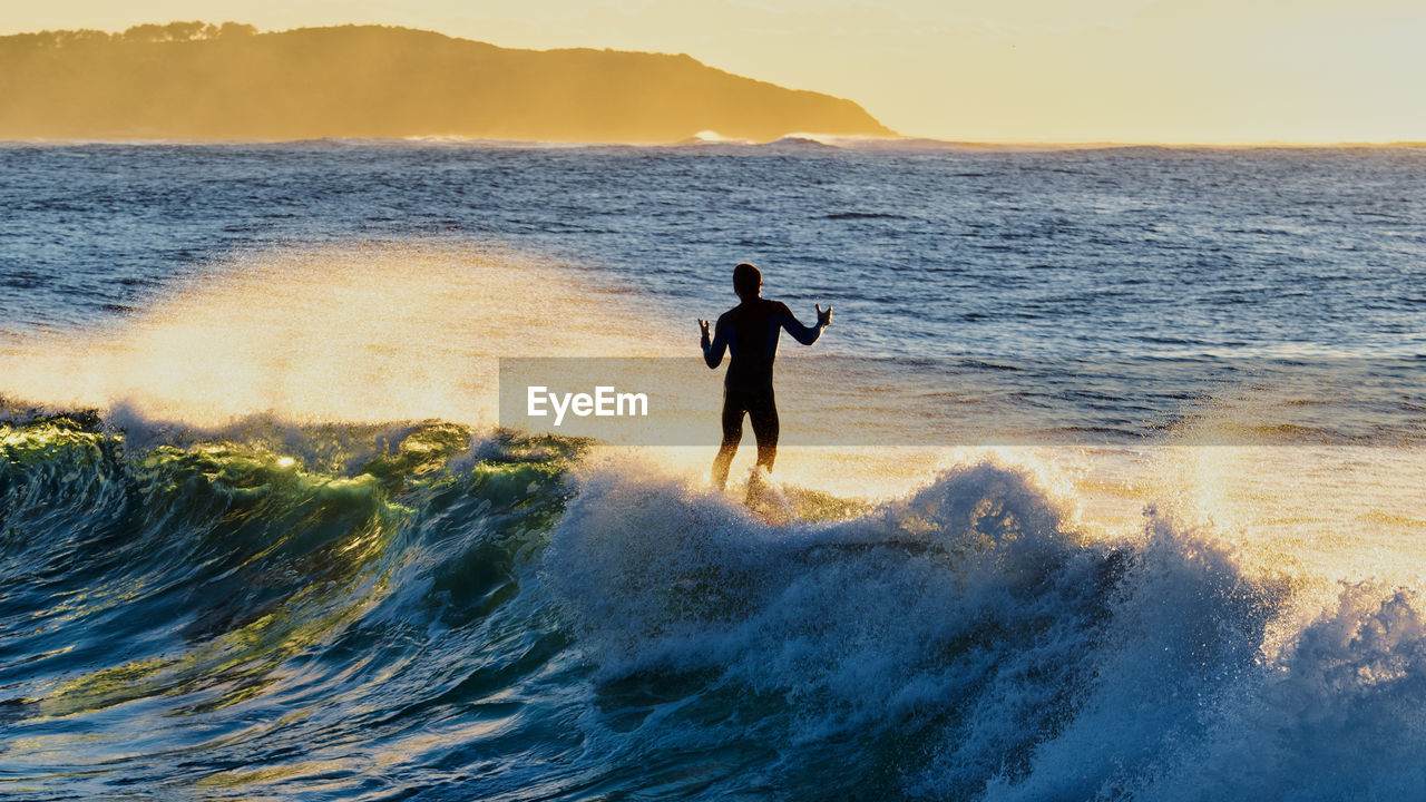 Silhouette man surfing in sea against sky during sunset