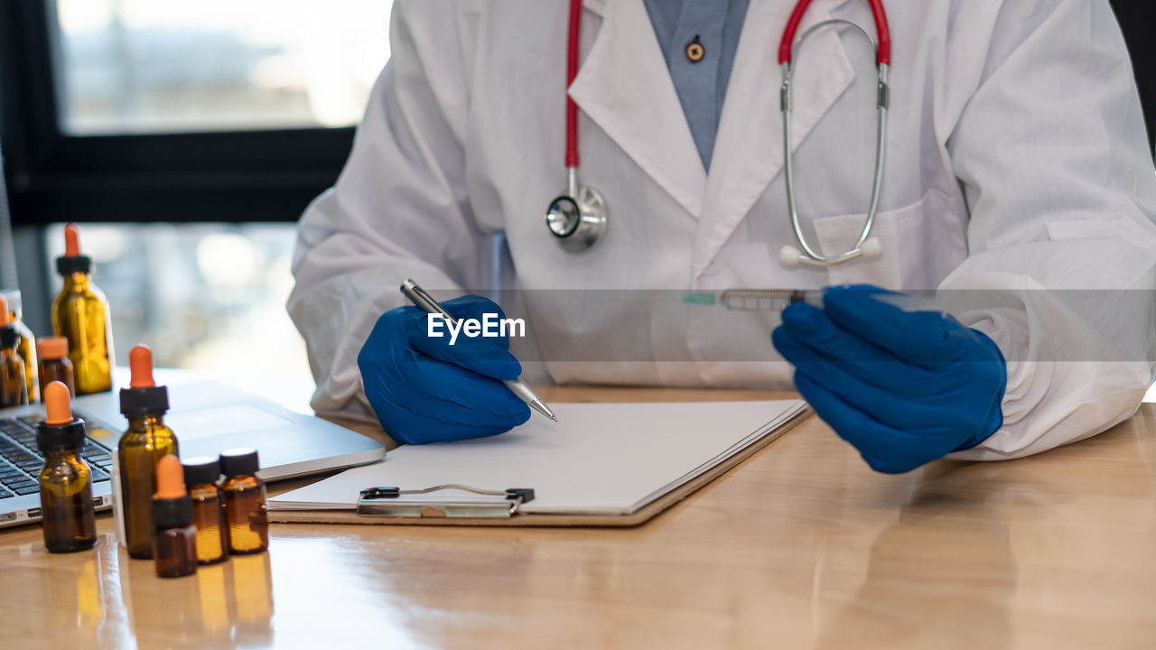 MIDSECTION OF MAN WORKING ON TABLE WITH PEOPLE