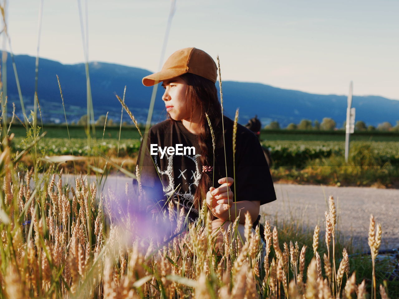 Woman sitting by plant against sky