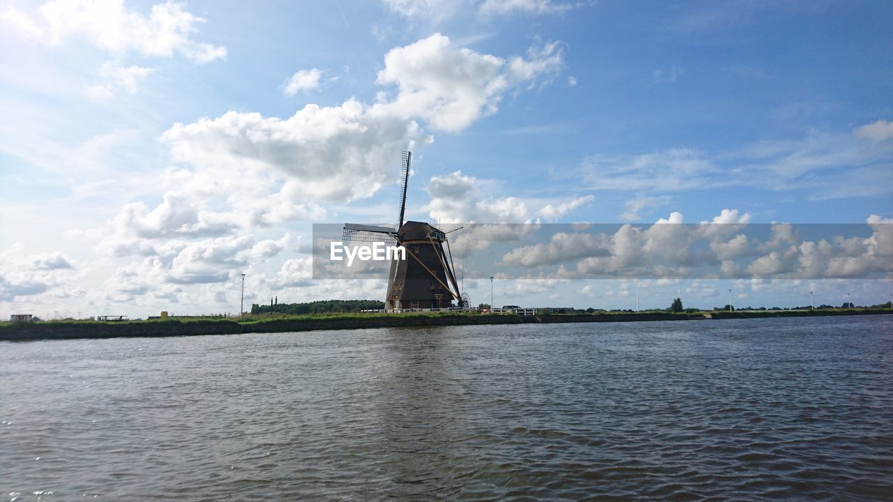 TRADITIONAL WINDMILL BY CRANES AGAINST SKY