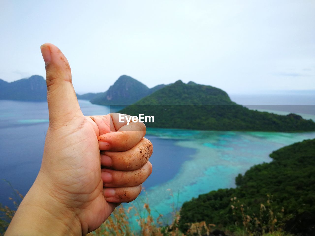 Close-up of hand with sea in background