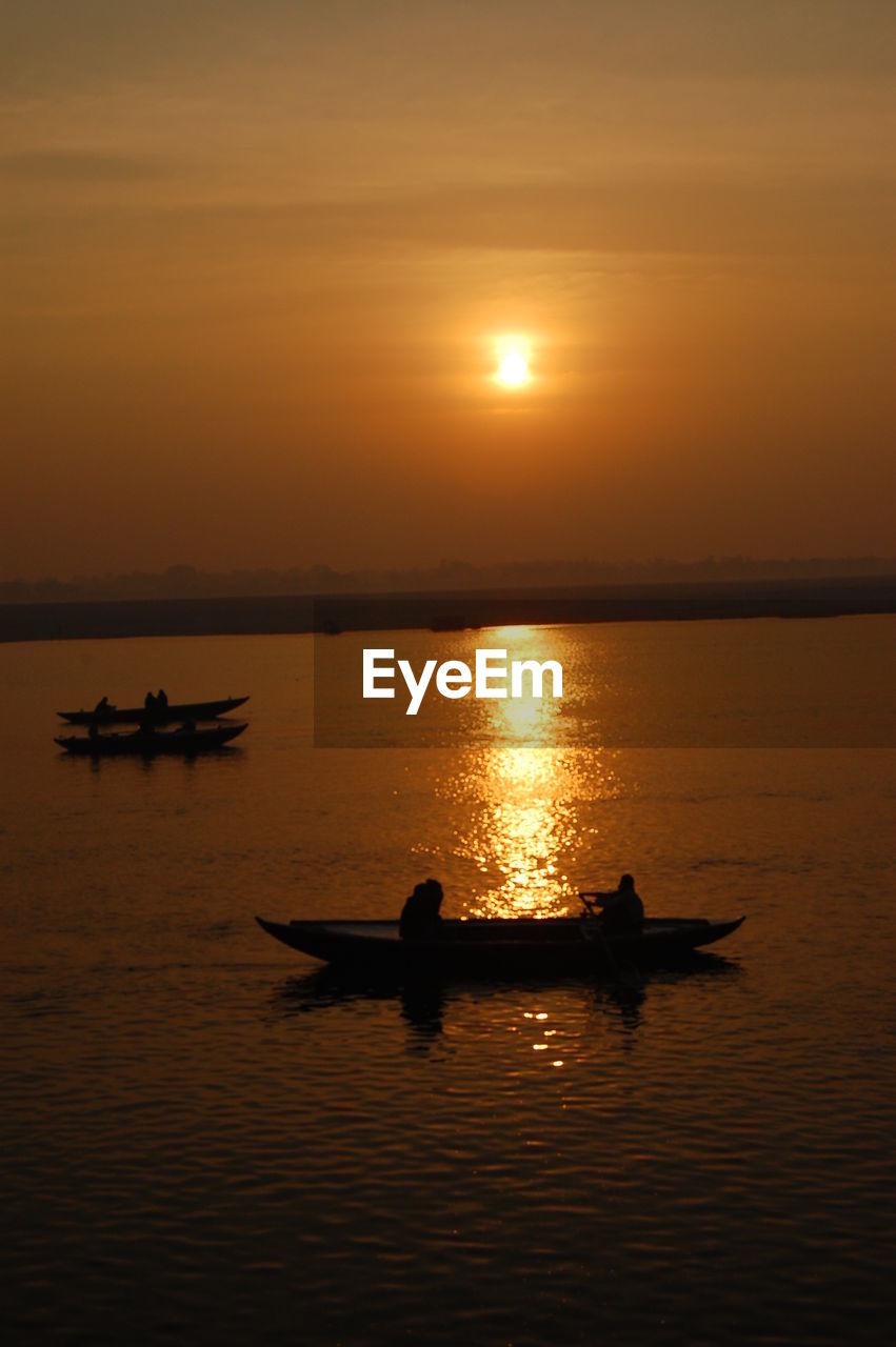 SILHOUETTE BOATS IN SEA AGAINST ORANGE SKY