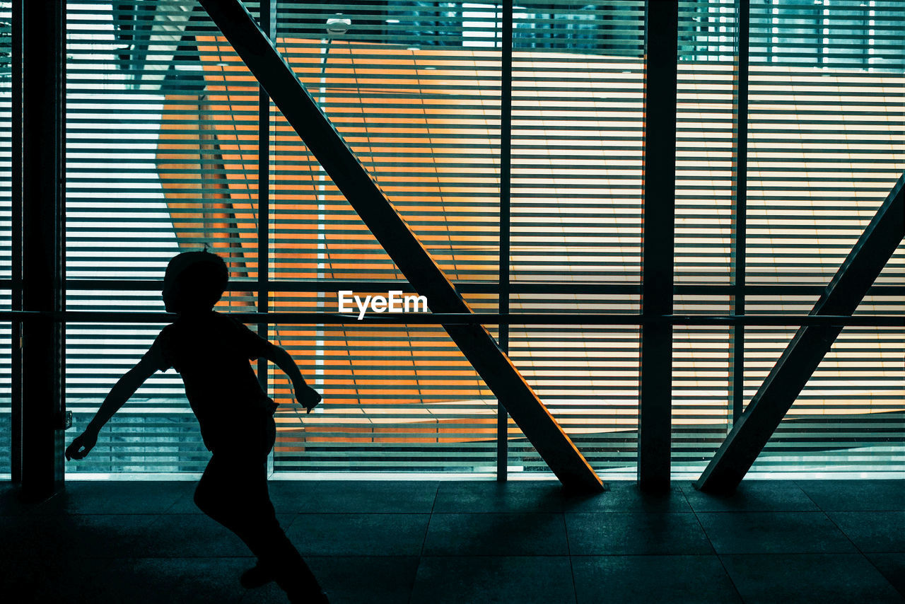 Silhouette boy running by window