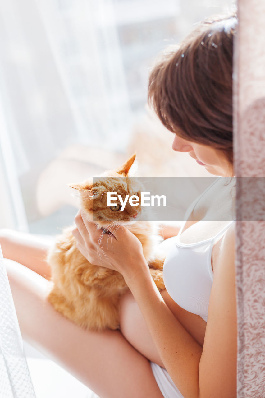 Pregnant woman in white underwear with cute ginger cat. risk of infection toxoplasmosis.