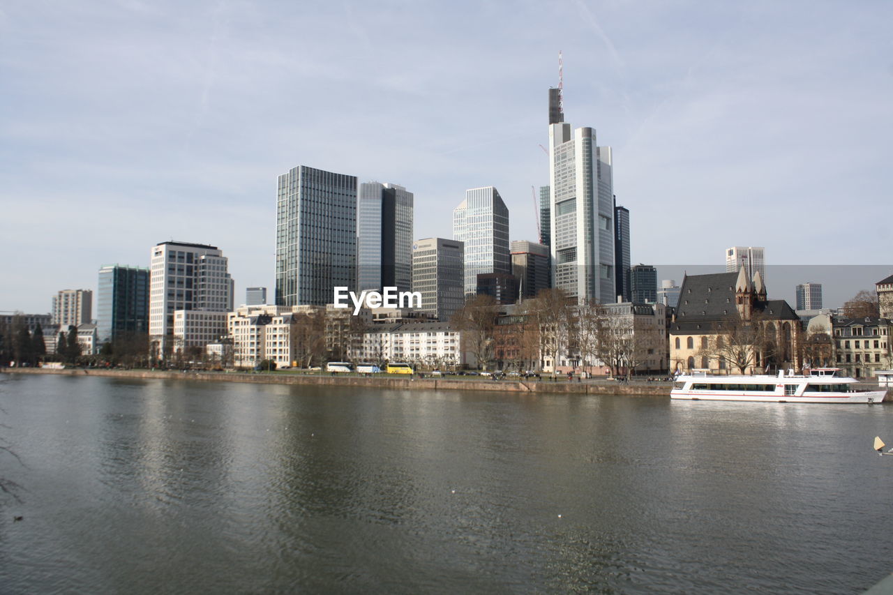 Sea by buildings against sky in city