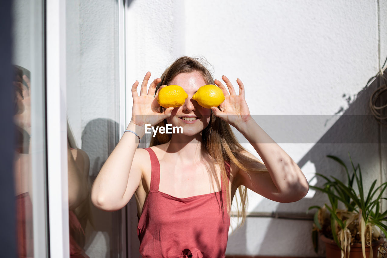 SMILING YOUNG WOMAN HOLDING FRUIT