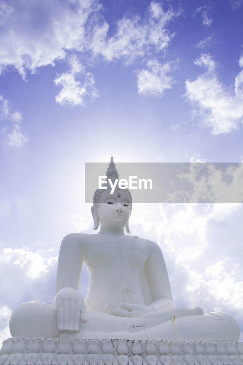 Low angle view of buddha statue against cloudy sky