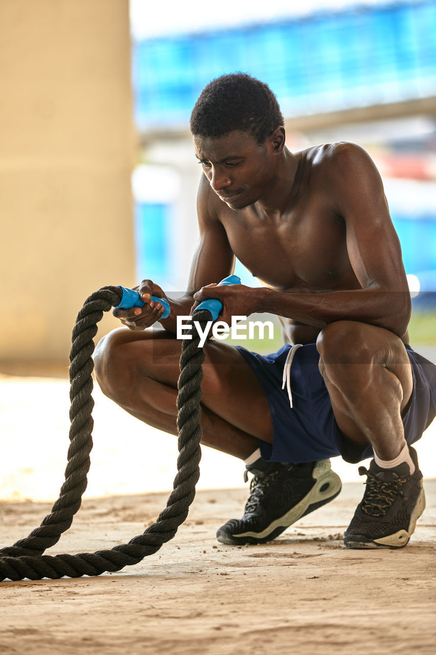 portrait of shirtless man exercising at beach