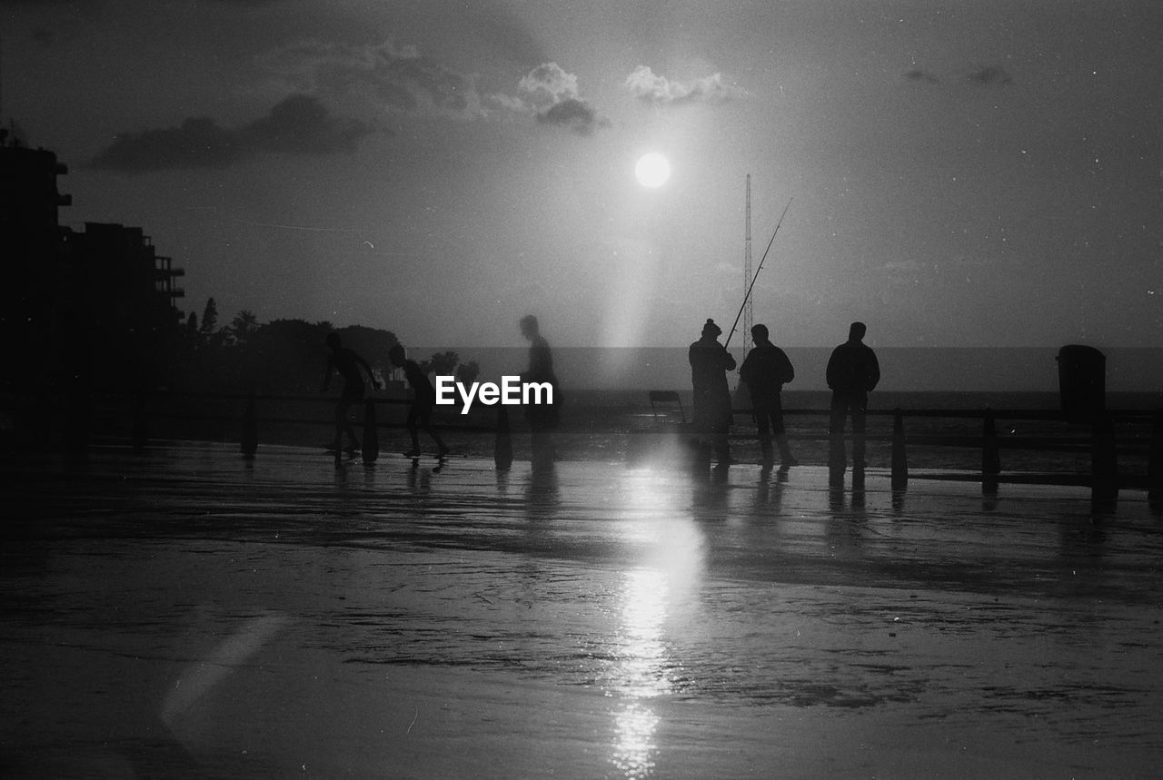 Silhouette people on coniche against sky during rainy season