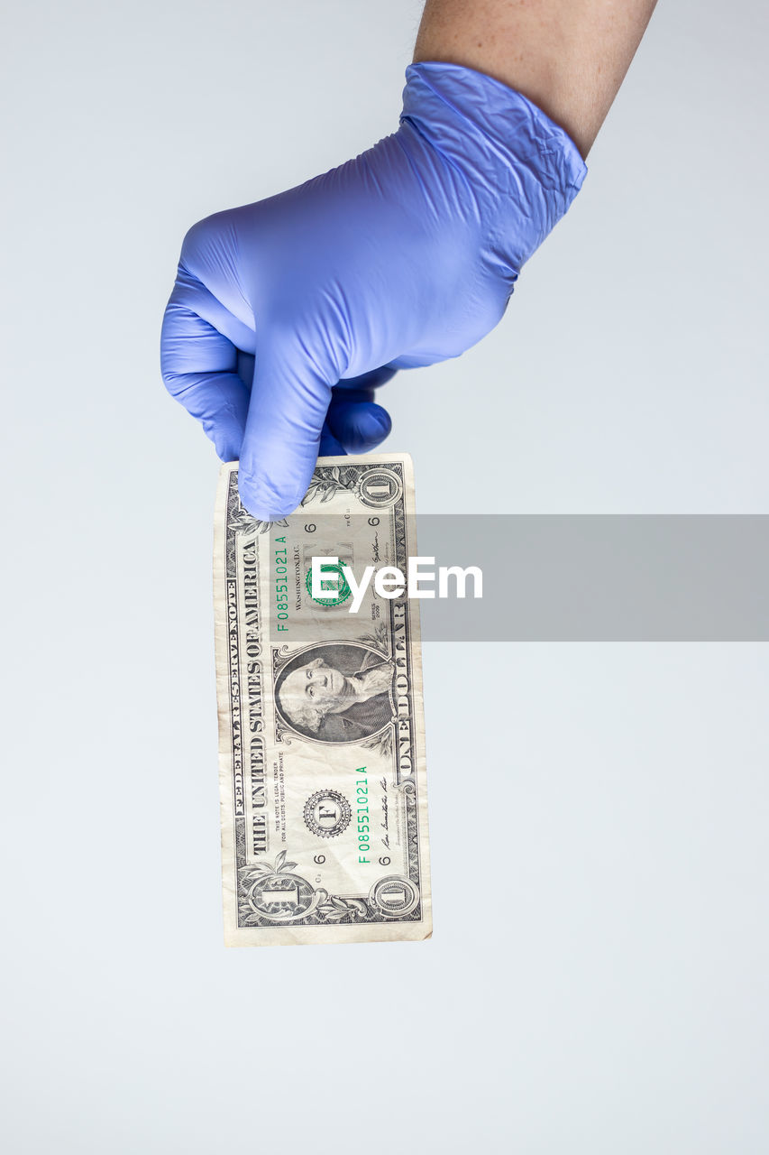 Cropped hand of woman holding paper currency over white background