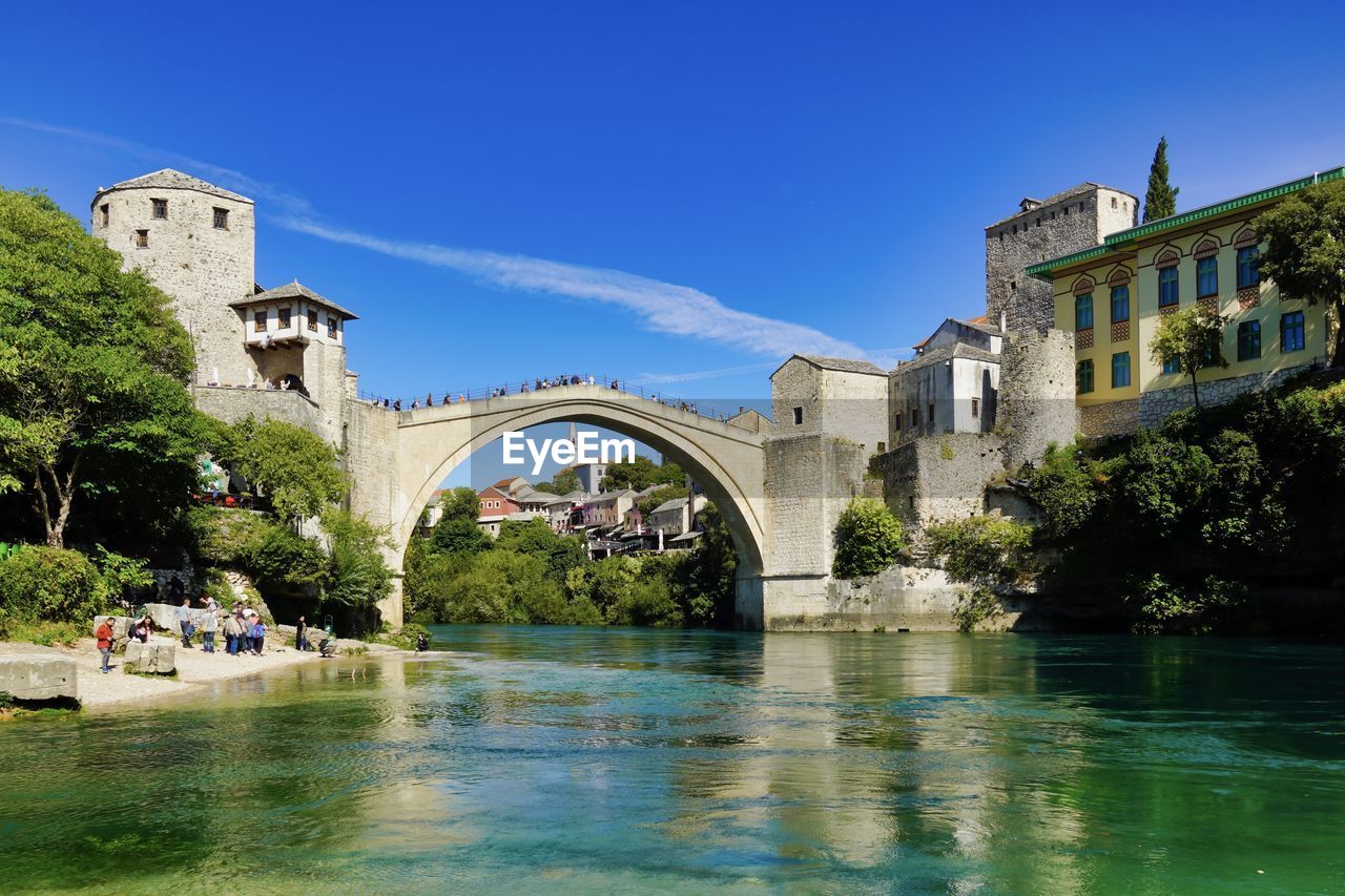 Arch bridge over river against buildings